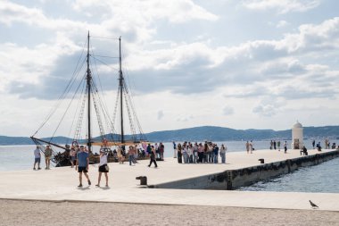 Zadar, Hırvatistan, 28 Ekim 2025, Adriyatik Denizi manzarası turistler ve beyaz bir deniz feneri ve bir yolcu gemisi.
