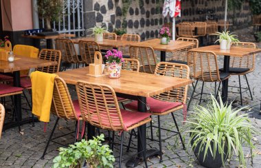 Yaz terasında çiçeklerle süslenmiş masaları olan rahat restoran dekorasyonu.