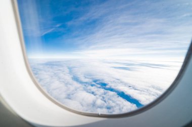 Bulutlardan oluşan bir uçaktan manzara, seyahat ederken pencereden güzel mavi bir gökyüzü