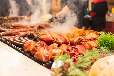 Satıcı, şehir merkezindeki Krakow Polonya 'daki Noel pazarında et ve sosis kızartıyor.