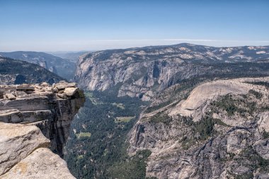 Vadiyi tepeden gören bir dağ sırası. Gökyüzü açık ve güneş parlıyor.
