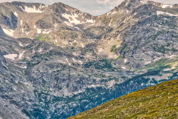 Önünde göl olan bir dağ sırası. Dağlar karla kaplı ve göl ağaçlarla çevrili. Huzurlu ve huzurlu bir manzara, karla kaplı dağlarla