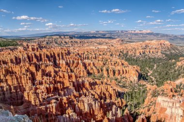 Uçsuz bucaksız, kırmızı bir kanyon ve bir sürü kırmızı kaya. Gökyüzü mavi ve arka planda bazı bulutlar var. Huzurlu ve huzurlu bir sahne.