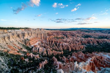 Açık mavi gökyüzü ile kırmızı kaya oluşumlarının güzel bir manzarası. Gökyüzü bulutlarla dolu, ortama huzurlu ve huzurlu bir atmosfer veriyor.