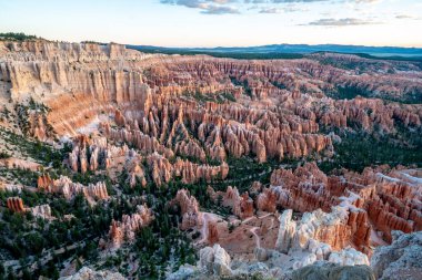 Bir sürü kırmızı kayanın olduğu güzel bir kanyon manzarası. Gökyüzü mavi ve turuncu karışımıdır.
