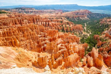 Bir sürü kırmızı kayanın olduğu güzel bir kanyon manzarası. Gökyüzü mavi ve güneş parlıyor.