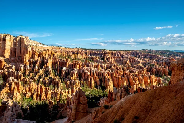 Kızıl kayalıkları ve dağları olan güzel, kayalık bir manzara. Gökyüzü açık ve mavidir, ve güneş parlıyor. Sahne huzurlu ve sakin, dağlarla birlikte.