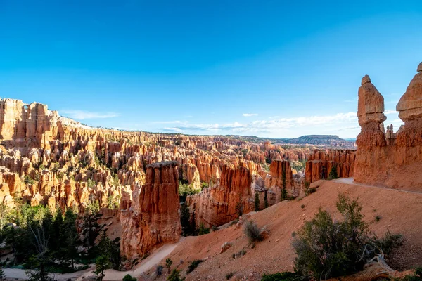 Bir sürü kızıl kaya oluşumları olan güzel bir manzara. Gökyüzü açık ve mavidir, ve güneş parlıyor. Huzurlu ve huzurlu bir manzara. Kayalar ve dağlar bir korku hissi yaratıyor.
