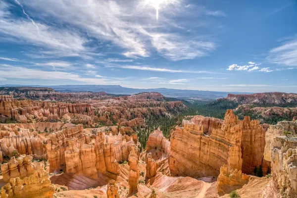 Gökyüzü mavi ve güneş parlıyor. Dağlar kahverengi ve kayalıktır. Manzara nefes kesici ve huzur verici.