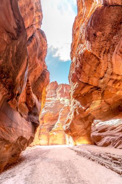 Üzerinde mavi bir gökyüzü olan dar bir kanyon. Kanyon kayalar ve toprakla dolu. Gökyüzü berrak ve parlak, ve güneş kanyon üzerinde parlıyor.