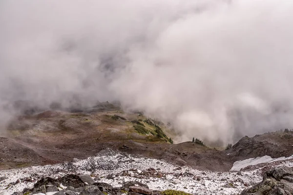 Bulutlar ve karla kaplı bir dağ sırası. Gökyüzü bulutlu ve bulutlar kalın