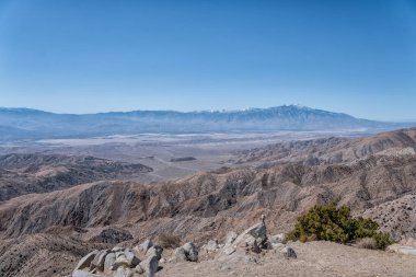 Arka planda açık mavi gökyüzü olan bir dağ sırası. Dağlar karla kaplı.