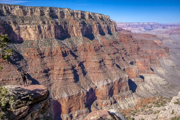 Kanyona bakan bir uçurumda duran bir insan. Manzara nefes kesici ve kişi anın tadını çıkarıyor gibi görünüyor.