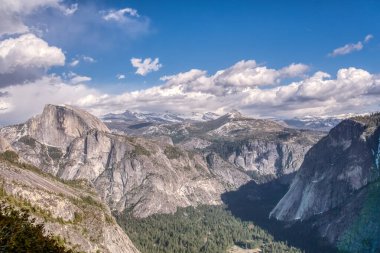 Dağlar karla kaplı ve gökyüzü mavi. Dağlar çok yüksek ve bulutlar gökyüzünü kaplıyor.