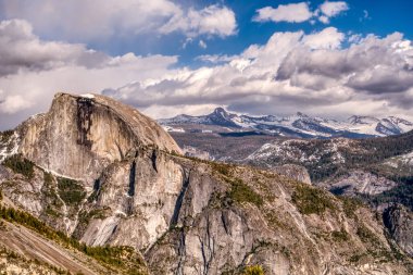 Dağ sırası karla kaplı ve gökyüzü bulutlu. Dağların zirveleri karla kaplı ve bulutlar gökyüzünde alçak