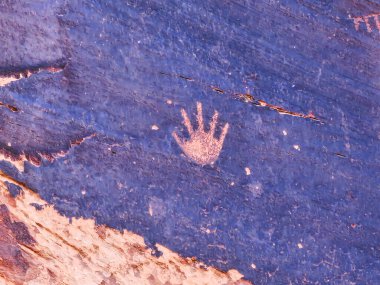 Mavi bir yüzeyde el izi var. El, parmak izinin tam ortasında ve görünen tek parçası. Mavi yüzey pürüzlüdür ve çok fazla dokusu vardır.
