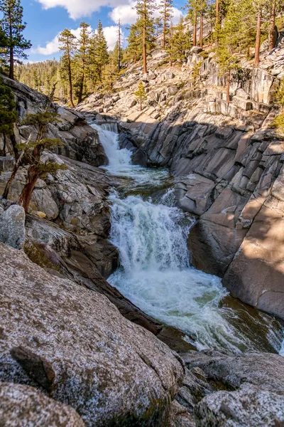 Bir şelale kayalık bir uçurumdan aşağı akıyor. Su berrak ve kayalar gri. Huzurlu ve huzurlu bir sahne.