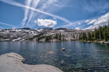 Arkasında dağ olan güzel bir göl. Gökyüzü açık ve mavidir birkaç bulutla