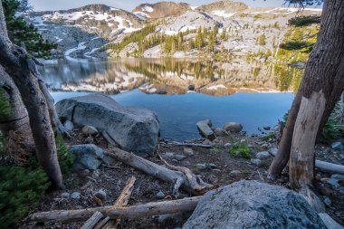 Suda dağların yansıması olan güzel bir göl. Sahne huzurlu ve huzurlu.
