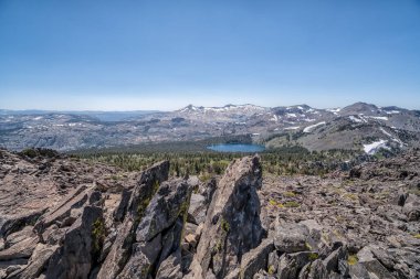 Uzakta gölü olan kayalık bir dağın tepesi. Gökyüzü açık ve mavi. Huzurlu ve huzurlu bir sahne.