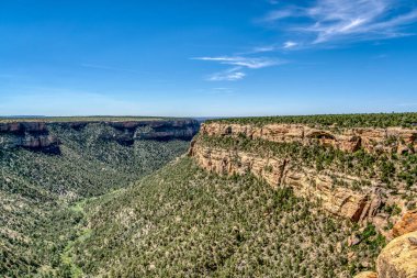 Aralarında vadi olan bir dağ sırası. Gökyüzü açık ve mavi. Vadi yemyeşil.