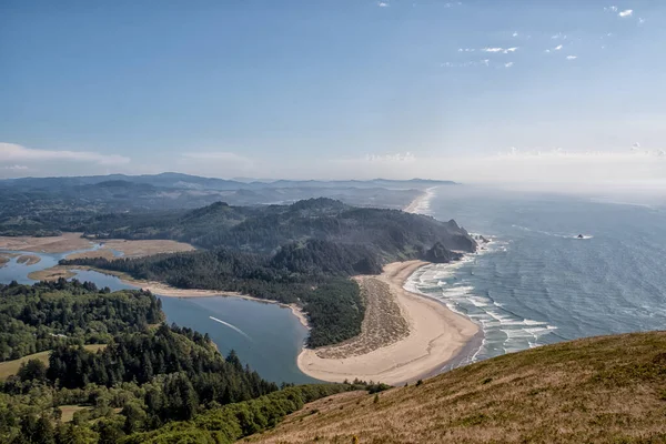 Arkasında dağ olan güzel bir sahil ve okyanus manzarası. Gökyüzü açık ve su sakin.
