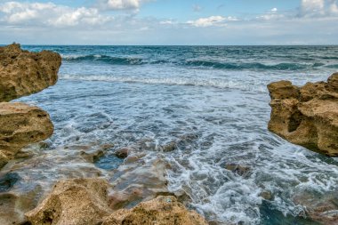 Okyanus sakin ve dalgalar küçük. Kayalar sudan fırlıyor ve su berrak.