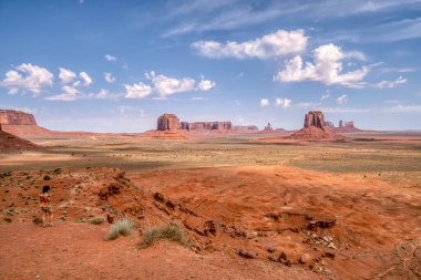 Arkasında birkaç dağ olan bir çöl manzarası. Gökyüzü açık ve mavi