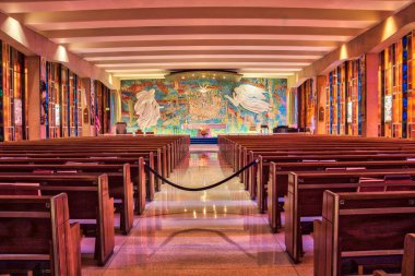 Vitraylı pencereleri ve sıraları olan büyük bir kilise. Sıralar boş ve kilise çok büyük.