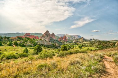 Açık mavi gökyüzü olan güzel bir dağ sırası. Dağlar kırmızı kayalarla kaplı. Çimler kuru ve kahverengi.