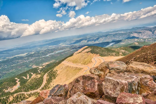 Tepesinde yol olan bir dağ. Yol dönüyor ve arka planda ağaçlar var.