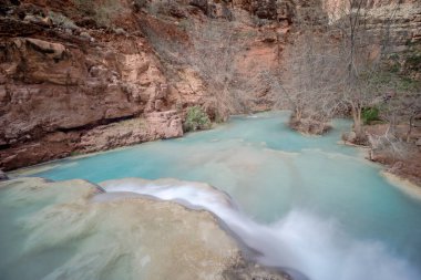 Güzel mavi bir nehir kayalık bir kanyon boyunca akar. Su kristal gibi berrak ve kayalar kahverengi. Sahne huzurlu ve sakin, suyun sesiyle.