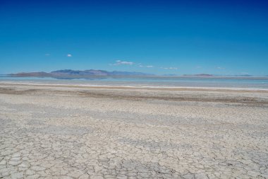 Arkasında mavi gökyüzü olan ıssız bir çöl manzarası. Gökyüzü açık ve güneş parlıyor.