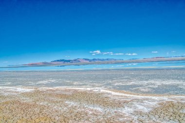 Arkasında mavi bir gökyüzü olan büyük, boş bir çöl. Gökyüzü açık ve güneş parlıyor.