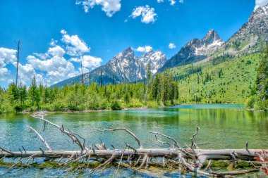 Önünde göl olan güzel bir dağ sırası. Göl sakin ve berrak, uzaktaki dağları yansıtıyor. Sahne huzurlu ve huzurlu.