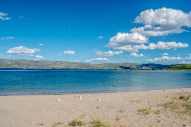 Sahil, sakin mavi bir okyanusa ve gökyüzünde birkaç buluta sahip sakin ve resim gibi bir yerdir. Gökyüzü parlak mavi bir renktir ve su kristal kadar berraktır.