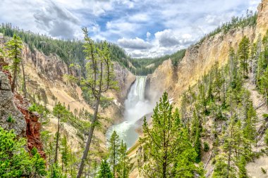 Önünde şelale olan güzel bir dağ sırası. Ağaçlar yemyeşil, gökyüzü açık ve mavidir. Huzurlu ve huzurlu bir sahne, ve huşu uyandırıyor.