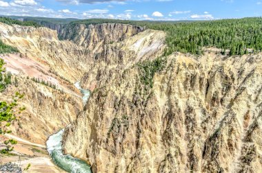 Arka planda bir dağ olan bir nehir bir kanyonun içinden akar. Su berrak ve dağ ağaçlarla kaplı.