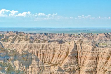 Gökyüzü mavi ve toprak kuru. Manzara çorak ve kayalık. Gökyüzü açık ve güneş parlıyor.