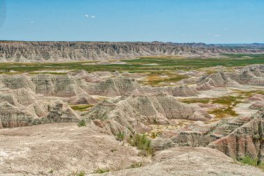 Uçsuz bucaksız, çorak bir arazi, etrafa saçılmış birkaç ağaç. Gökyüzü açık ve mavidir ve güneş ışıl ışıl parlar.