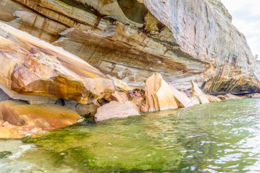 Kayalık bir uçurum bir su kütlesini gözden kaçırır. Su yeşil ve kayalar kahverengi.