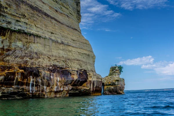 İçinde şelale ve ağaç olan bir uçurum. Uçurum taştan yapılmış ve su sakin.
