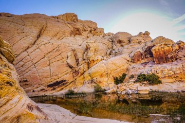 İçinden nehir akan kayalık bir dağ. Güneş batıyor, sahne üzerine sıcak bir parıltı saçıyor.