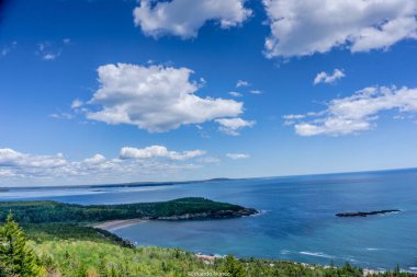 Bulutları ve büyük bir su kütlesi olan güzel mavi bir gökyüzü. Gökyüzü açık ve su sakin.