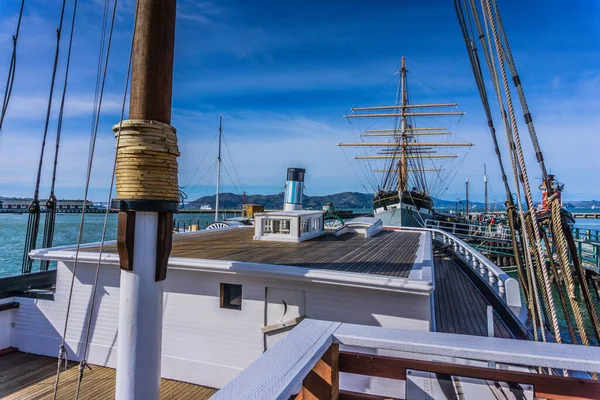 Beyaz kapaklı ve tahta güverteli büyük bir gemi. Gemi rıhtıma yanaştı.