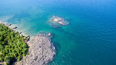 Okyanus sakin ve mavi. Kayalık bir kıyı şeridi var. Su temiz ve kayalar kıyı şeridine dağılmış.