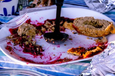 Üzerinde kaşık ve sol tarafında çatal olan bir tabak yemek. Tabak yemekle dolu ve üzerinde bir sürü sos var.