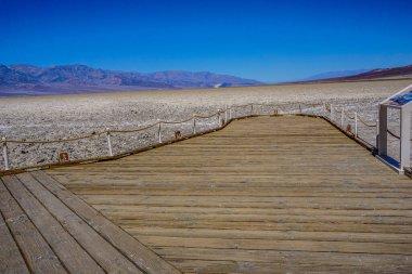 Yan tarafında çit olan tahta bir tahta kaldırım. Sahil yolu boş ve gökyüzü mavi.