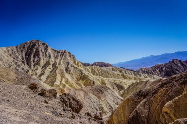 Dağlar sarı kayalarla kaplıdır ve gökyüzü mavidir. Dağlar çok yüksek ve gökyüzü çok berrak.