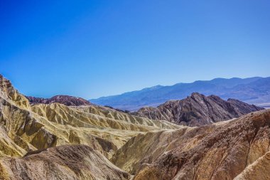 Dağlar sarı ve kahverengi kayalarla kaplıdır. Gökyüzü mavi ve berrak. Dağlar çok yüksek ve gökyüzü çok berrak.